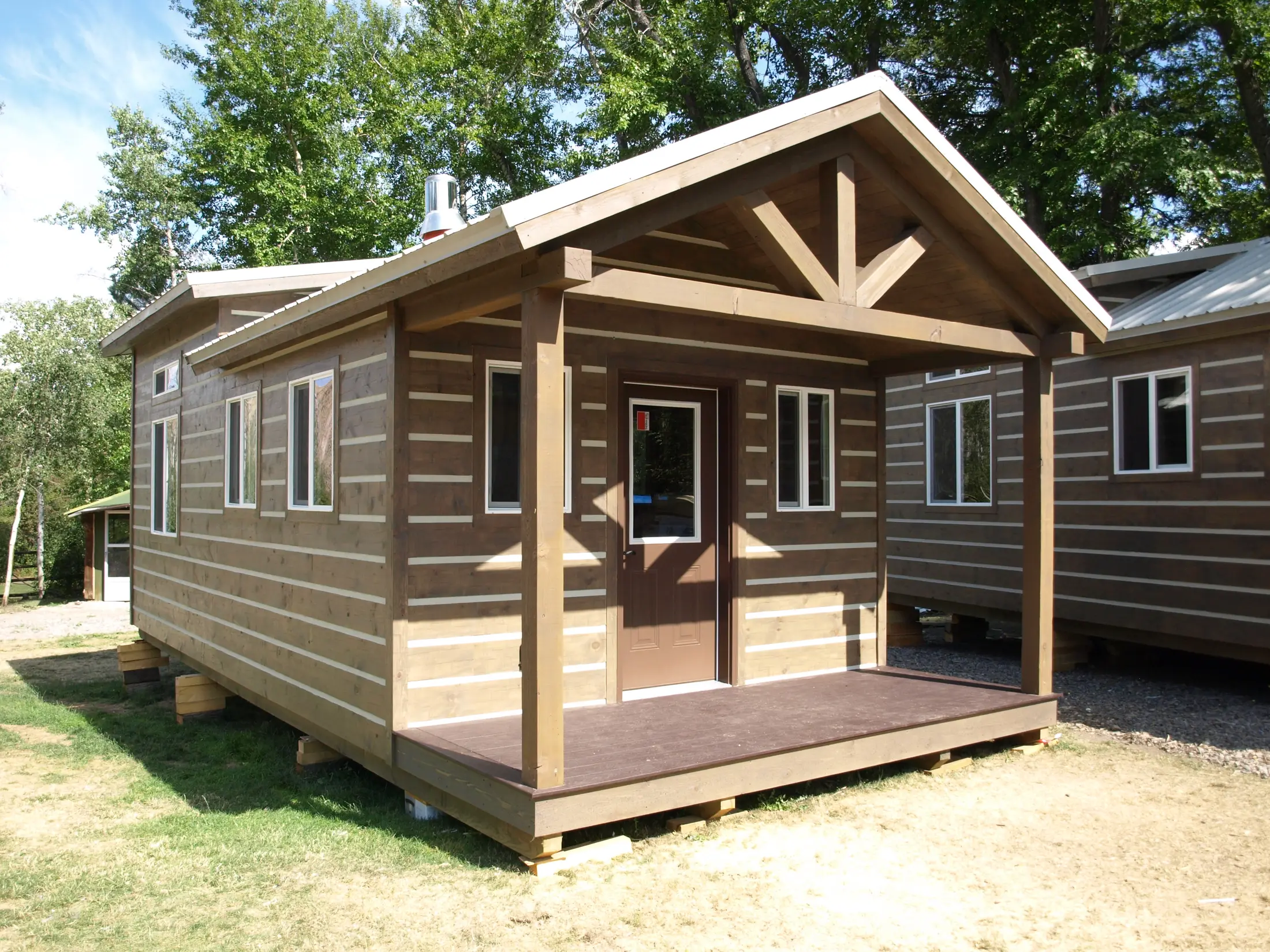 Alpine Cottage portable cabin with a covered timber-frame porch in the Cabins Plus build yard