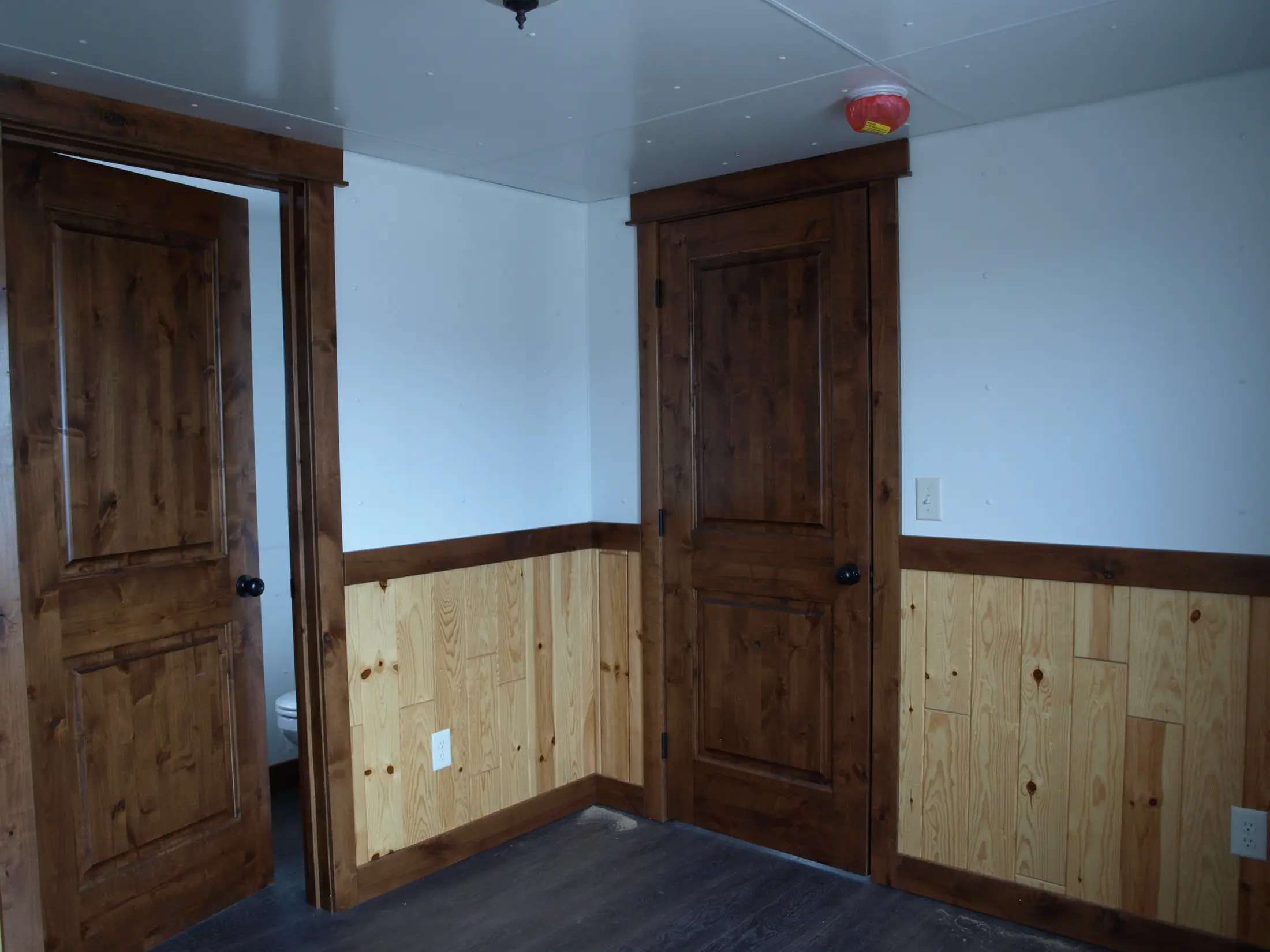 Cabin bedroom with knotty pine wainscot and alder doors